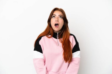 Genç kızıl saçlı kadın beyaz arka planda izole edilmiş yukarı bakıyor ve şaşırmış bir ifadeyle