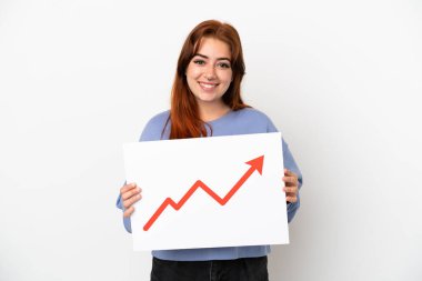 Beyaz arka planda izole edilmiş genç kızıl saçlı kadın elinde büyüyen bir istatistik okuyla mutlu bir ifade ile bir işaret tutuyor.