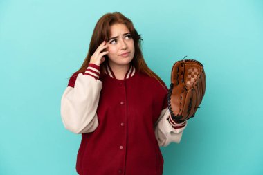 Beyzbol oynayan genç kızıl saçlı kadın mavi arka planda izole edilmiş, kuşkuları ve düşünceleri var.