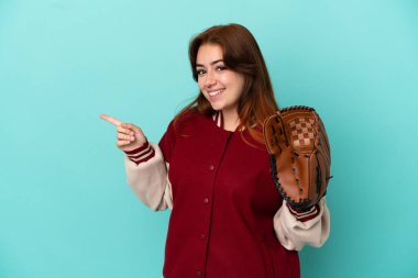 Beyzbol oynayan genç kızıl saçlı kadın, mavi arka planda soyutlanmış, parmaklarını kenarı işaret ediyor.