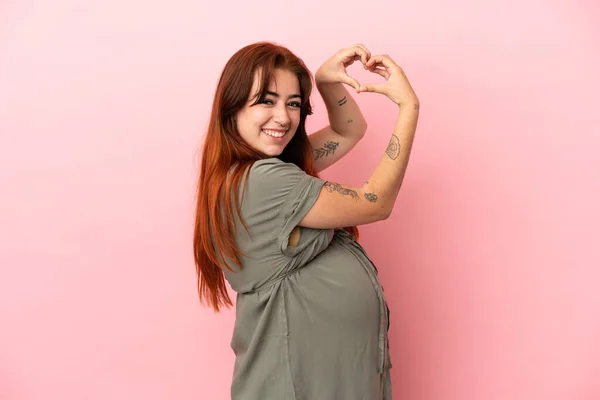 Young Redhead Caucasian Woman Isolated Pink Background Pregnant Making Heart — ストック写真