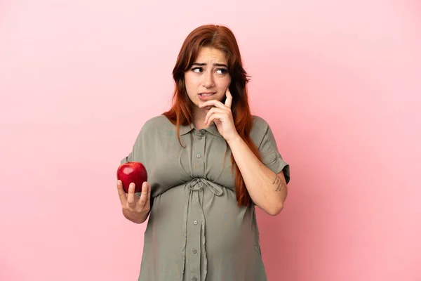 Młoda Ruda Kaukaska Kobieta Odizolowana Różowym Tle Ciąży Trzymając Jabłko — Zdjęcie stockowe
