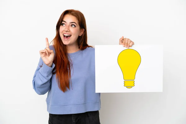 Young Redhead Woman Isolated White Background Holding Placard Bulb Icon — Stock Photo, Image