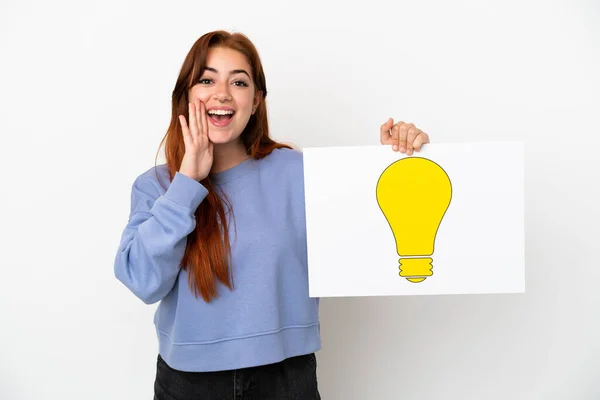 Young Redhead Woman Isolated White Background Holding Placard Bulb Icon — Zdjęcie stockowe