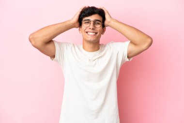 Arjantinli genç adam pembe arka planda yalnız gülüyor.