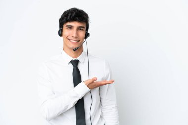 Tele pazarlamacı beyaz arka planda izole edilmiş bir kulaklıkla çalışırken bir fikir sunuyor ve gülümsüyor.