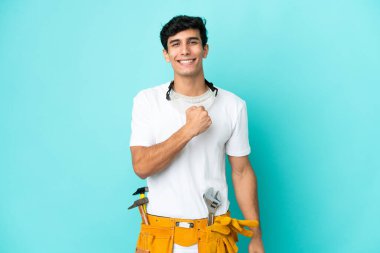 Genç elektrikçi Arjantinli adam mavi arka planda zaferi kutluyor.