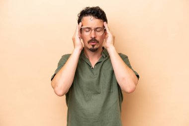 Beyazlı genç bir adam bej arka planda izole edilmiş baş ağrısı var.