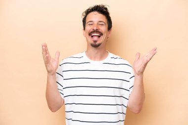 Beyazlı genç bir adam bej arka planda izole edilmiş, çok gülümsüyor.