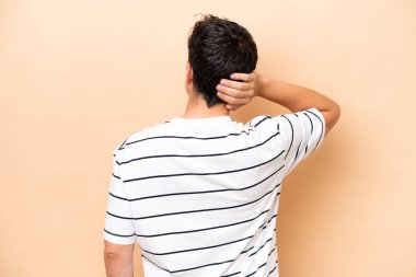 Beyazlı genç adam bej arka planda izole edilmiş ve düşünüyor.