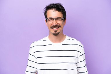 Mor arka planda gözlüklü ve mutlu bir ifadeyle izole edilmiş genç beyaz bir adam.