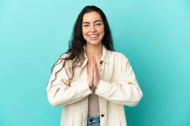 Mavi arka planda izole edilmiş genç beyaz kadın avuç içlerini bir arada tutuyor. İnsan bir şey ister.