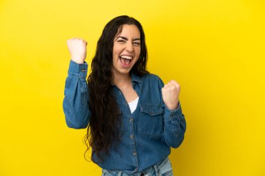 Sarı arka planda izole edilmiş beyaz bir kadın zaferi kutluyor.