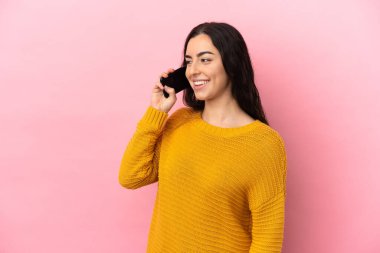 Pembe arka planda izole edilmiş cep telefonu kullanan beyaz bir kadın.