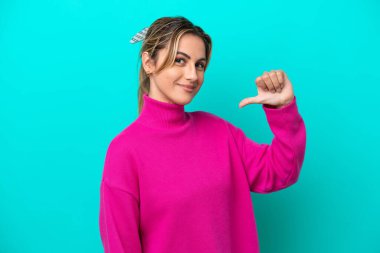 Mavi arka planda soyutlanmış, gururlu ve kendini beğenmiş beyaz bir kadın.