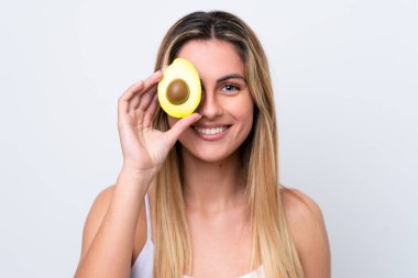Beyaz arka planda izole edilmiş beyaz bir kadın elinde bir avokado tutarken gülümsüyor. Portreyi kapat