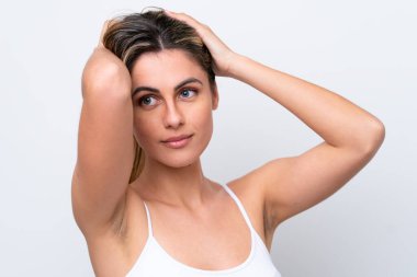 Beyaz arka planda izole edilmiş genç beyaz kadın saçlarına dokunuyor. Portreyi kapat