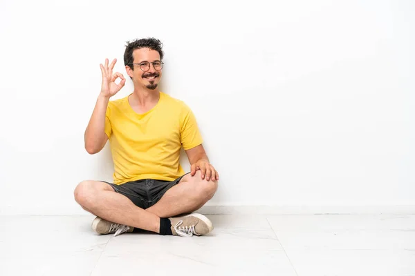 Young Caucasian Man Sitting Floor Isolated White Background Showing Sign — Photo