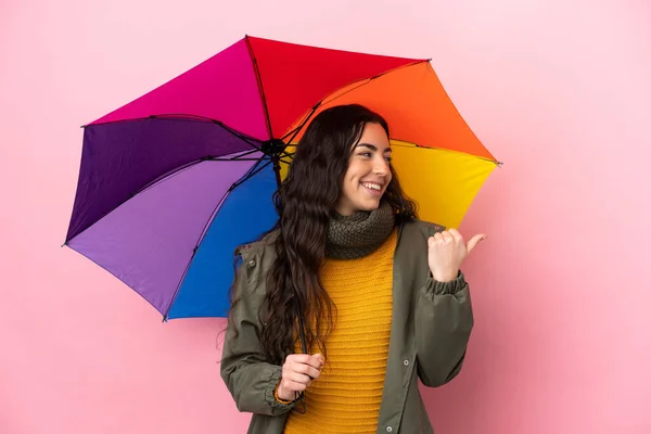 Mujer Joven Sosteniendo Paraguas Aislado Sobre Fondo Rosa Apuntando Hacia — Foto de Stock