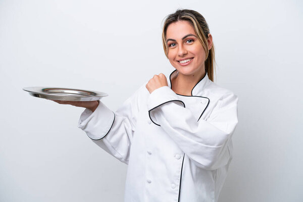 Young chef woman with tray isolated on white background celebrating a victory