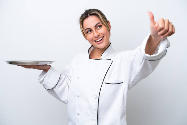 Young chef woman with tray isolated on white background giving a thumbs up gesture