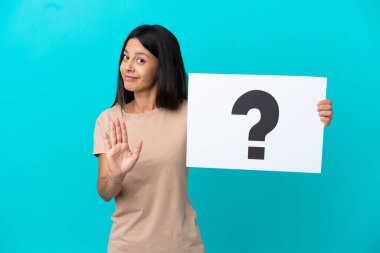 Arka planda izole edilmiş genç bir kadın soru işareti olan bir pankart tutuyor ve dur işareti yapıyor.