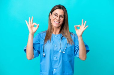 Mavi arka planda izole edilmiş orta yaşlı cerrah kadın parmaklarıyla 
