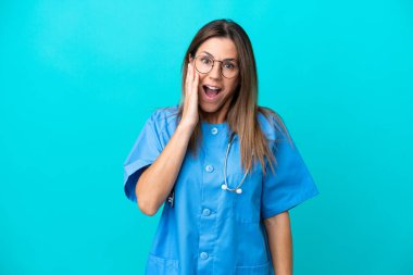 Orta yaşlı cerrah kadın mavi arka planda izole edilmiş, şaşırmış ve şok olmuş bir yüz ifadesi var.