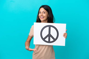 Tecrit edilmiş genç bir kadın. Elinde barış sembolü olan bir pankart tutuyor ve onu işaret ediyor.