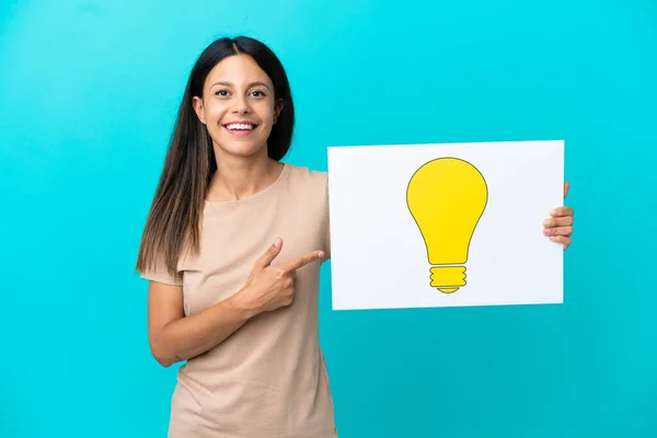 Young Woman Isolated Background Holding Placard Bulb Icon Pointing — Stock Photo, Image
