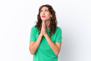 Young woman with curly hair isolated on white background keeps palm together. Person asks for something