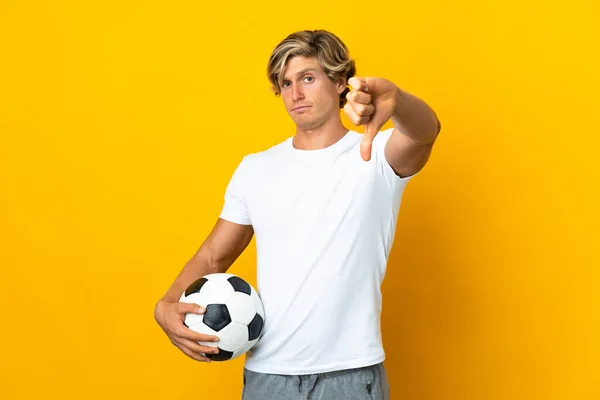 English football player over isolated yellow background showing thumb down with negative expression