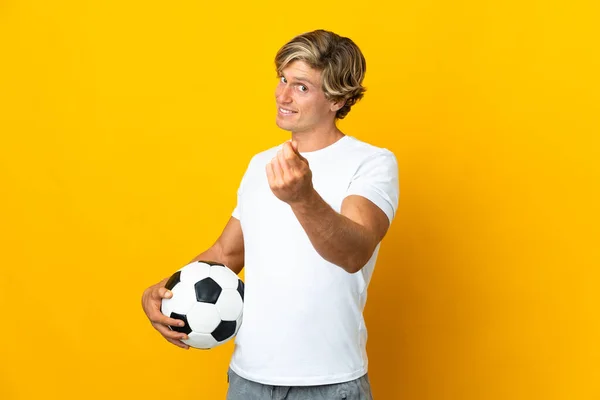 English football player over isolated yellow background making money gesture