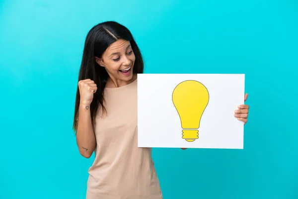 Young Woman Isolated Background Holding Placard Bulb Icon Celebrating Victory — Stock Photo, Image