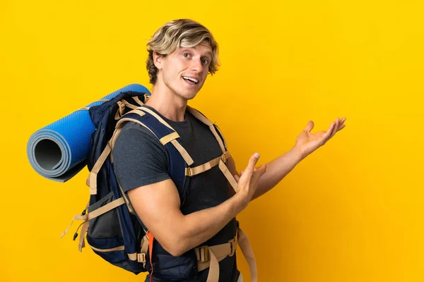 Jonge Bergbeklimmer Man Geïsoleerde Gele Achtergrond Reikende Handen Naar Zijkant — Stockfoto