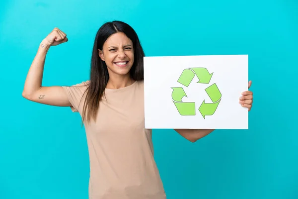 Young Woman Isolated Background Holding Placard Recycle Icon Doing Strong — стоковое фото