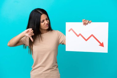 İzole edilmiş arka planda, elinde azalan bir istatistik ok sembolü ve kötü sinyal veren bir tabela tutan genç bir kadın.