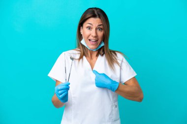Mavi arka planda, sürpriz bir yüz ifadesi olan orta yaşlı doktor kadın.
