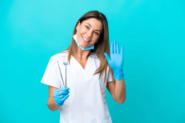Médico Meia Idade Mulher Isolada Fundo Azul Saudando Com Mão — Fotografia de Stock