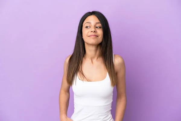 Young caucasian woman isolated on purple background having doubts while looking side