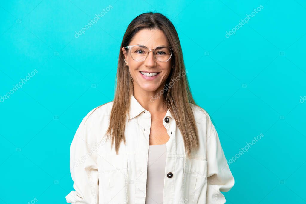 Middle age caucasian woman isolated on blue background With glasses with happy expression
