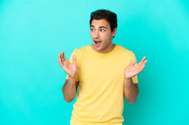 Kafkasyalı yakışıklı, yalıtılmış mavi arka planda, şaşırmış bir yüz ifadesi var.