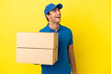 Yalıtılmış sarı duvarda gülen teslimatçı.