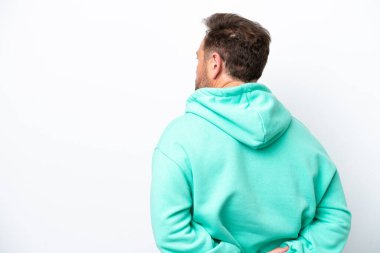 Orta yaşlı beyaz bir adam beyaz arka planda izole edilmiş ve arkasına bakıyor.