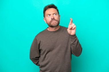 Orta yaşlı beyaz bir adam mavi arka planda izole edilmiş, şans diliyor ve en iyisini diliyor.