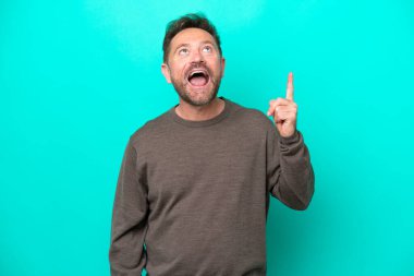 Orta yaşlı, beyaz bir adam mavi arka planda izole edilmiş ve şaşırmış.