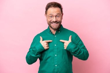 Orta yaşlı beyaz bir adam pembe arka planda izole edilmiş, şaşırmış bir yüz ifadesi var.