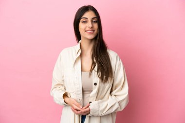 Pembe arka planda izole edilmiş genç beyaz kadın gülüyor.