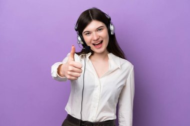 Telemarketer Russian woman working with a headset isolated on purple background with thumbs up because something good has happened