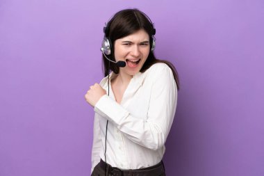 Telemarketer Russian woman working with a headset isolated on purple background celebrating a victory